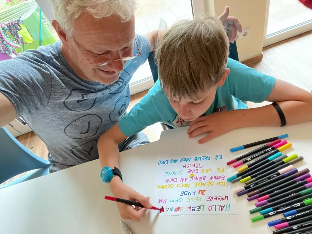 Einzelfallhelfer und Kind schreiben einen Brief mit buten Stiften